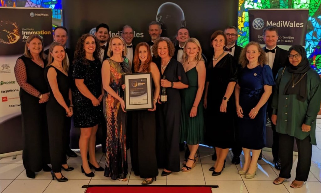 Image shows people gathered together holding an award