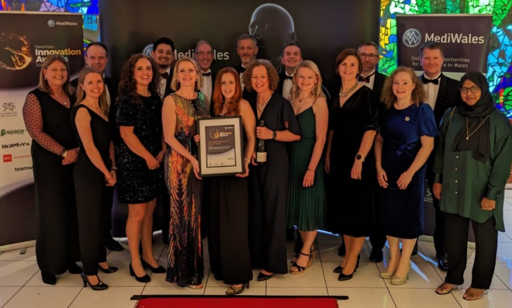 Image shows people gathered together holding an award